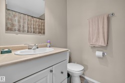Bathroom featuring a vanity with a laminate countertop and integrated sink, a chrome two-handle faucet, white cabinetry with silver-tone hardware, and a toilet - 