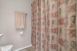 Bathroom featuring a patterned shower curtain, light-colored walls, and a white toilet - 