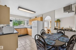 U-shaped kitchen featuring light wood cabinetry, dark countertops, and a bay window - 