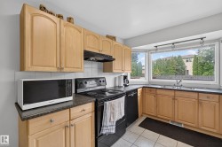 Kitchen featuring light wood-finish cabinetry, dark countertops, and a tile backsplash - 