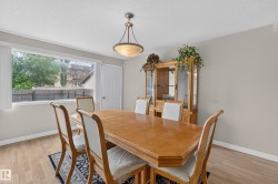Dining area featuring wood-finish flooring, a large window with white blinds, and neutral-toned walls - 