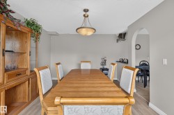 Dining area featuring wood-finish flooring, a contemporary chandelier, and an arched entryway - 