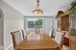 Dining area featuring wood-finish flooring, a contemporary pendant light fixture, a large window, a paneled door, and neutral wall tones - 
