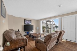 Living area with wood-finish flooring, neutral wall paint, and a white entrance door - 