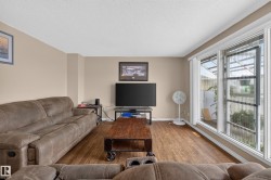 Living space featuring wood-finish flooring, neutral wall tones, and extensive windowing - 