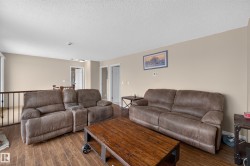 Spacious upper-level room featuring wood-finish flooring, neutral wall paint, and a white textured ceiling - 