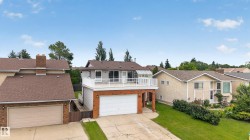 Elevated deck with white railing, sunroom, attached two-car garage, and brick detailing - 