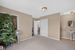 Carpeted room with a built-in closet, neutral wall paint, and a wall-mounted light fixture - 