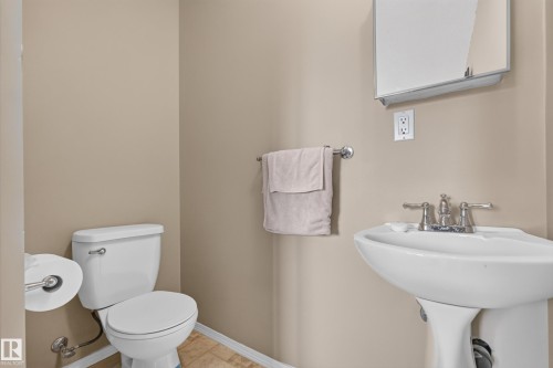 Pedestal sink with chrome faucet, white toilet, and neutral wall paint - 3841 62 Street, Edmonton, AB 