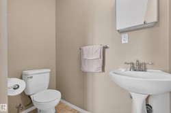 Pedestal sink with chrome faucet, white toilet, and neutral wall paint - 