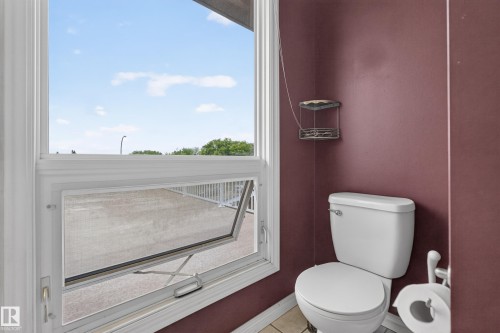 White casement window with an open screen, showcasing a large exterior patio area - 3841 62 Street, Edmonton, AB 