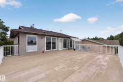 Expansive concrete deck featuring white railings, a sunroom with a glass roof, and sliding glass doors providing access to the interior - 
