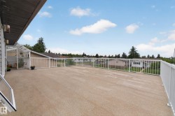 Expansive outdoor deck featuring textured concrete flooring and a white railing system - 