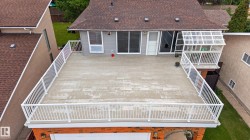Expansive rooftop deck featuring white railings and a concrete surface - 