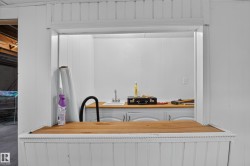 Service window featuring a wood-finish countertop and white beadboard paneling - 