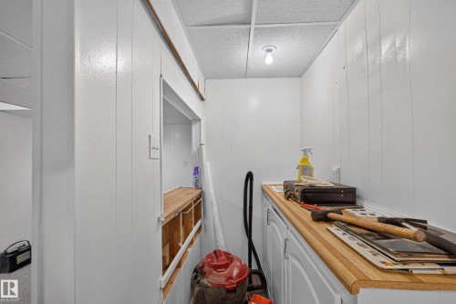 Utility space featuring wood-finish countertops, white cabinetry, a built-in sink, and white beadboard paneling - 3841 62 Street, Edmonton, AB 