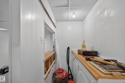 Utility space featuring wood-finish countertops, white cabinetry, a built-in sink, and white beadboard paneling - 