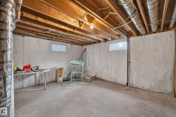 Unfinished basement with concrete flooring and exposed wooden ceiling joists - 