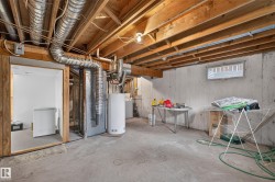 Unfinished basement featuring exposed wood joists, concrete walls, and a visible water heater - 