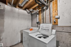 Basement utility area featuring exposed concrete walls and ceiling joists - 