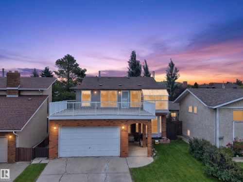 Two-story residence featuring a ground-level garage, second-story balcony, brick accents, and a sunroom extension - 3841 62 Street, Edmonton, AB 