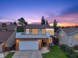 Two-story residence featuring a ground-level garage, second-story balcony, brick accents, and a sunroom extension - 