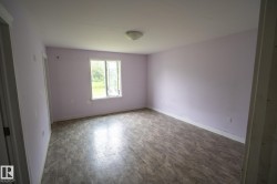 Spacious room featuring wood-finish flooring, a light purple wall color, and a white framed window - 