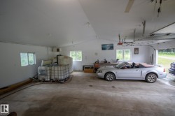Spacious garage featuring a high-pitched ceiling, multiple windows, concrete flooring, and an overhead garage door - 