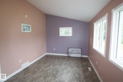 Room featuring wood-finish flooring, white baseboards, and a combination of pink and purple painted walls - 