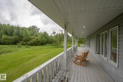 Expansive covered porch featuring a painted wood-finish floor and white baluster railing - 