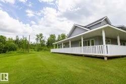 Expansive green lawn bordering a residence with gray siding and white trim - 