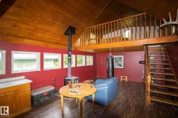 Open-concept room featuring wood-finish flooring, a wood-burning stove, and multiple windows - 