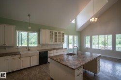 Kitchen featuring a central island with an undermount sink and a gooseneck faucet - 