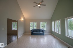 Vaulted ceilings with a ceiling fan, multiple windows offering abundant natural light, and neutral-toned flooring - 