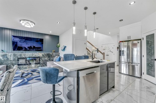Open-concept living area with a contemporary kitchen island featuring an undermount sink and integrated dishwasher - 5809 65 Street, Beaumont, AB - Indoor Photo Showing Kitchen With Stainless Steel Kitchen With Upgraded Kitchen