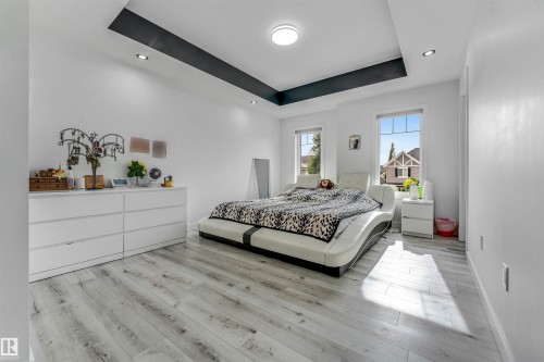 Spacious room featuring light wood-finish flooring, a tray ceiling with recessed lighting, and two windows - 5809 65 Street, Beaumont, AB - Indoor Photo Showing Bedroom