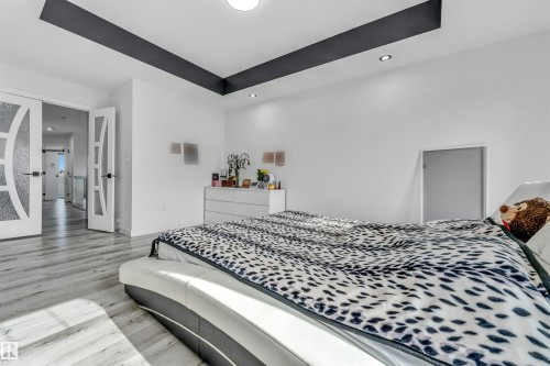 Spacious room featuring light wood-finish flooring, a tray ceiling with a dark accent, recessed lighting, and a white wall finish - 5809 65 Street, Beaumont, AB - Indoor Photo Showing Bedroom