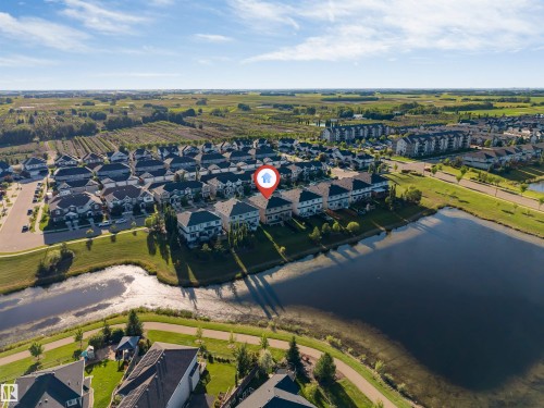 Aerial property perspective highlighting a residential community with a large body of water, green spaces, and paved pathways - 5809 65 Street, Beaumont, AB - Outdoor With View