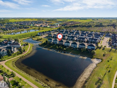 Aerial perspective highlighting a residential development with a large central pond - 5809 65 Street, Beaumont, AB - Outdoor With View