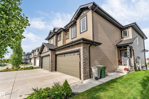 Modern townhome exterior featuring dual-tone siding, stone accents, and a two-car garage - 5809 65 Street, Beaumont, AB - Outdoor