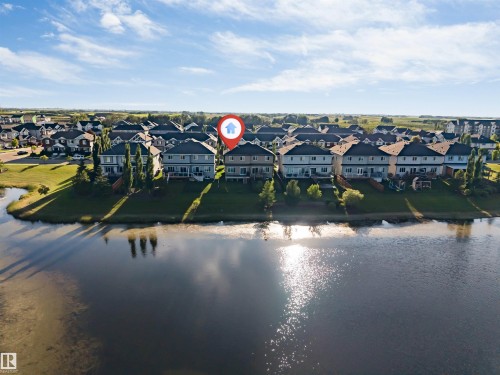 Waterside property featuring a multi-story rear elevation with multiple windows, a private deck, and a manicured lawn - 5809 65 Street, Beaumont, AB - Outdoor With Body Of Water With View