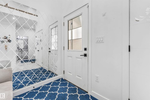 Entryway featuring a white paneled door with frosted glass inserts, black hardware, and a patterned area rug - 5809 65 Street, Beaumont, AB - Indoor Photo Showing Other Room