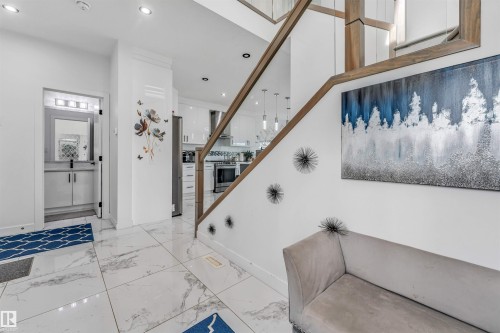 Expansive open-concept foyer featuring large format marble-look tile flooring, a contemporary staircase with wood-finish handrail and glass panels, and recessed ceiling lighting - 5809 65 Street, Beaumont, AB - Indoor Photo Showing Other Room