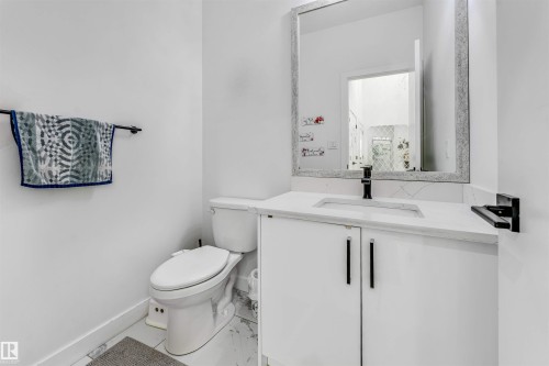 Powder room featuring a white single-sink vanity with a light-toned countertop, a rectangular undermount sink, and a black faucet - 5809 65 Street, Beaumont, AB - Indoor Photo Showing Bathroom