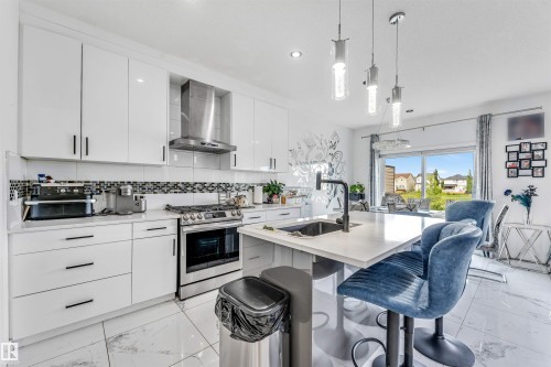 Modern kitchen featuring white cabinetry, stainless steel appliances, a center island with sink, and pendant lighting - 5809 65 Street, Beaumont, AB - Indoor Photo Showing Kitchen With Upgraded Kitchen