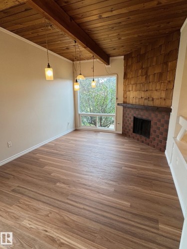 Bright interior space featuring wood-finish flooring, a wood-paneled ceiling with exposed beam, and pendant lighting - 482 Lee Ridge Road Nw, Edmonton, AB 