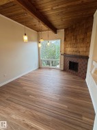 Bright interior space featuring wood-finish flooring, a wood-paneled ceiling with exposed beam, and pendant lighting - 