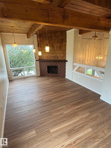 Spacious living area featuring wood-finish flooring, exposed wood beams, and a prominent brick fireplace with a shiplap-style surround - 482 Lee Ridge Road Nw, Edmonton, AB 