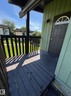 Covered exterior porch with dark-stained wood-finish flooring and matching railing - 