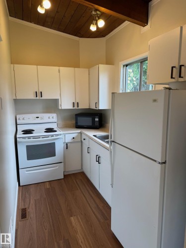 Kitchen featuring wood-finish flooring, white cabinetry with black hardware, and light-toned countertops - 482 Lee Ridge Road Nw, Edmonton, AB 